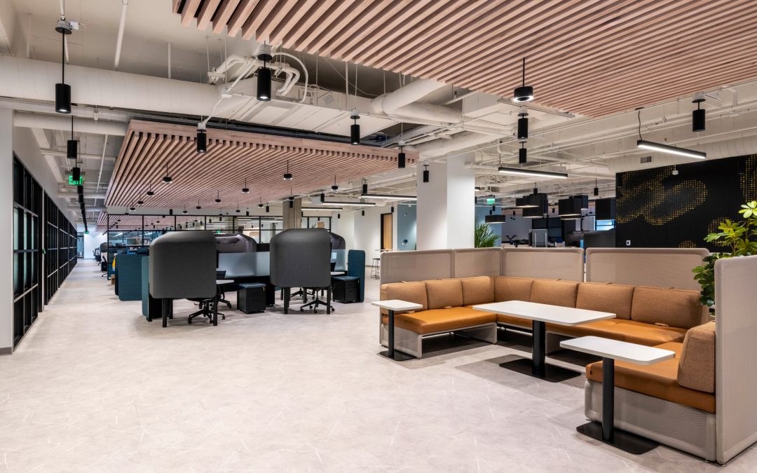 Vusion’s Dallas office with wood slat ceilings, screened workstations, and tan sectional seating around white tables