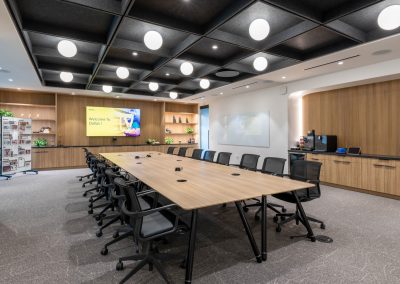 Vusion conference room with a long wood table, black chairs, built-in cabinetry, and globe lights within a dark ceiling grid